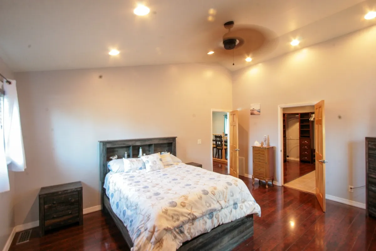 A serene bedroom featuring a comfortable bed, nightstand, wardrobe, and doorways leading to other parts of the suite. The room exudes a sense of calm, ideal for relaxation and restful sleep.