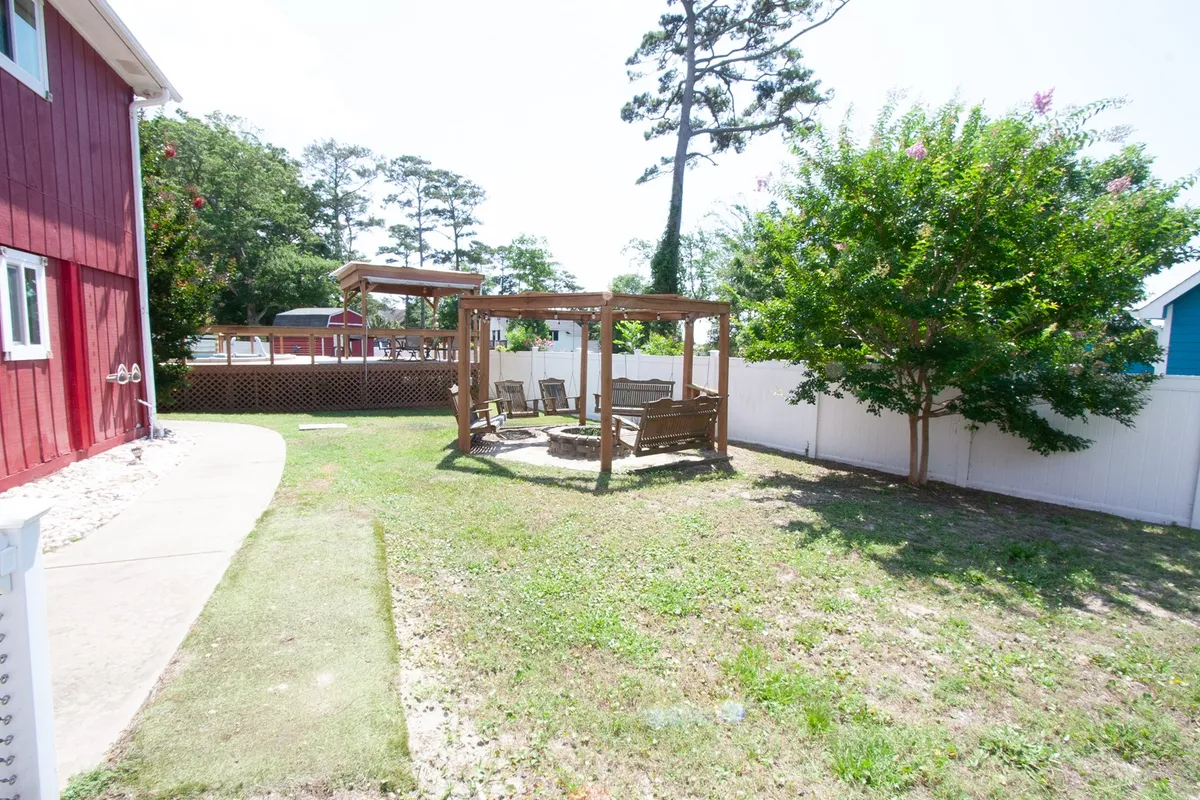 This image depicts a charming exterior setting featuring a wooden gazebo with swing chairs nestled under a lush green tree. The inviting outdoor area is ideal for relaxation or gathering with family, offering a tranquil atmosphere with sunset views from the gazebo and the potential for morning coffee in the swing chairs.